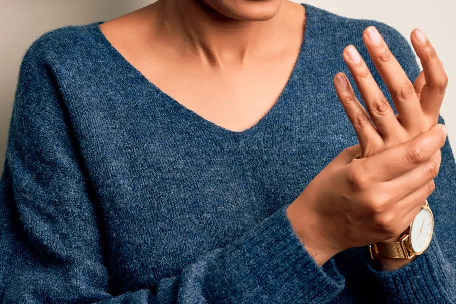 Arthritis-Doctor Close up of a woman in a blue sweater massaging one aching hand with the other. Get help for arthritis from Dr. David Lans in New Rochelle.