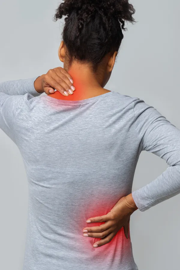 Fibromyalgia-Treatment An image from behind of a woman suffering from Fibromyalgia holding her hands on her neck and lower back. Get fibromyalgia treatment from Dr. David Lans in New Rochelle.