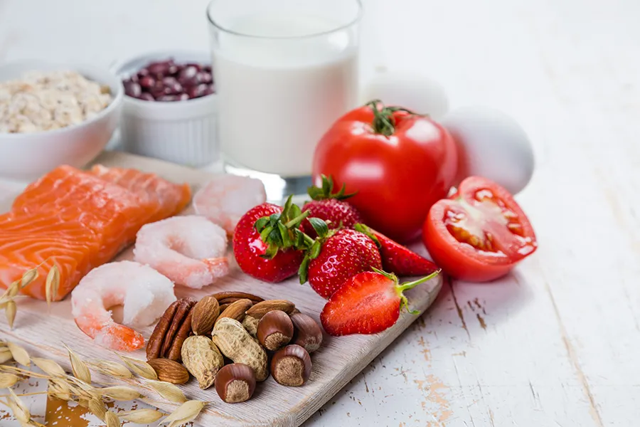 Food-Allergies-Clinic A board with healthy fruits and vegetables on a white wooden table. Get care for food allergies from Dr. David Lans in New Rochelle.