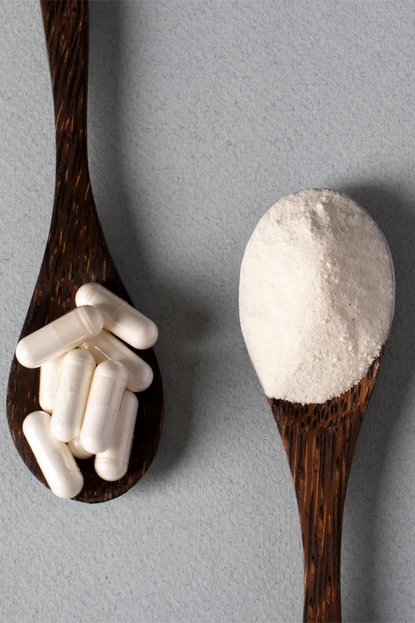 Two wooden spoons on a table, on with white powder and one with capsules, representing peptide therapy from Dr. David Lans in New Rochelle.