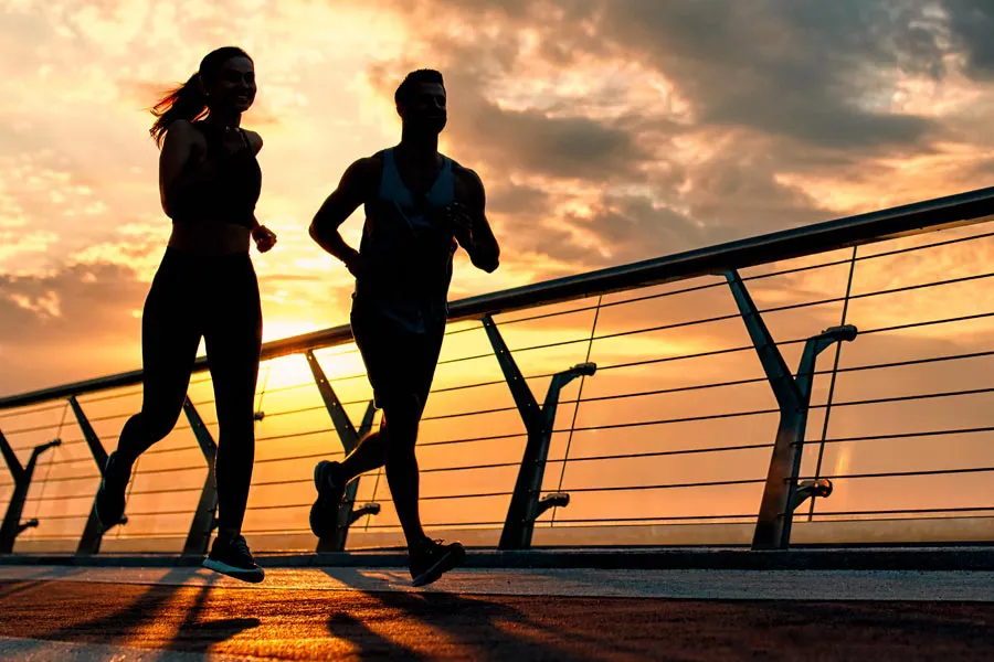Performance-Enhancing-Peptides-Doctor A couple jogging on a bridge at sunrise, representing performance enhancing peptide therapy from Dr. David Lans in New Rochelle.