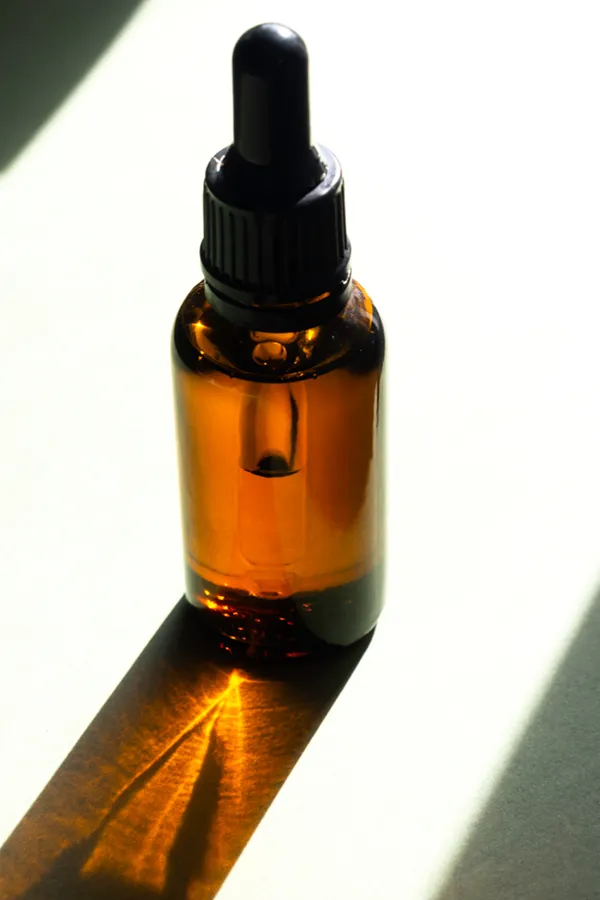 Performance-Enhancing-Peptides-Treatment A brown dropper bottle on a table lit by sunlight, representing performance enhancing peptide treatment from Dr. David Lans in New Rochelle.