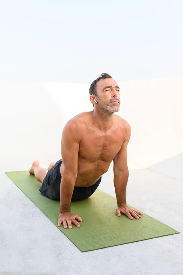 A middle-aged man doing yoga on a green mat after getting Rheumatology treatment from Dr. David Lans in New Rochelle.