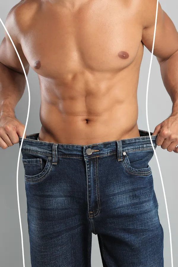 Semaglutide-Weight-Loss-Treatment A strong shirtless man in jeans holds the waistlines of his too-big jeans to show the success of semaglutide weight loss from Dr. David Lans in New Rochelle.