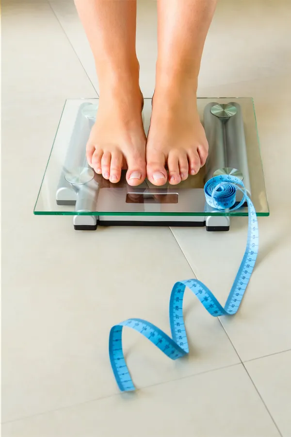 Weight-Loss-Resistance-Treatment Close-up of a woman's feet standing on a scale, with measuring tape by her toes, getting treatment for weight loss resistance from Dr. David Lans in New Rochelle.